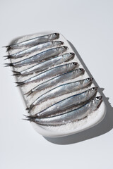 Anchoas frescas dentro de un plato lleno de sal sobre fondo blanco