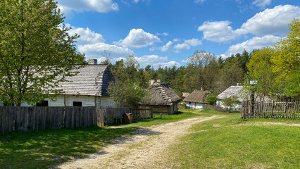 Polish old wooden countryside with sandy path during summer time with blue light cloudy sky