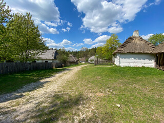 Polish old wooden countryside with sandy path during summer time with blue light cloudy sky