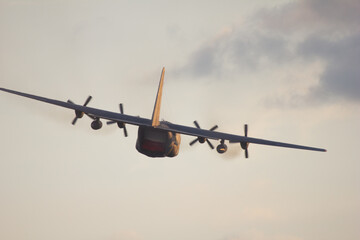 C-130 Hercules Departing at Sunset. A C-130 Hercules aircraft gracefully soars into the sunset at the Leszno Air Show, its silhouette capturing the beauty of flight and the golden hour.