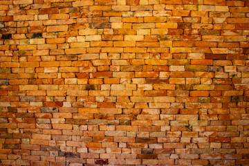 Rustic Wall of Bricks. A wide view of a rustic brick wall with warm hues, showcasing an uneven, textured pattern perfect for vintage or industrial design inspiration.