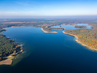 A captivating aerial view of a large lake bordered by lush forests, small islands, and docked...