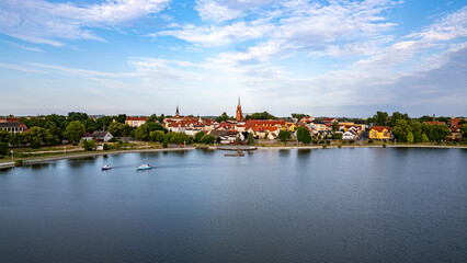 Picturesque Lake Raduń in Wałcz, Poland. Tranquil waters of Lake Raduń with colorful town buildings, scenic promenade, and boats gliding on the surface in Wałcz, Poland.