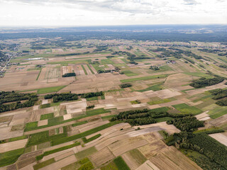 Naklejka premium Patchwork Fields from Above, A broad aerial view showcasing a mosaic of farmlands, where diverse fields form a geometric tapestry extending toward the distant horizon