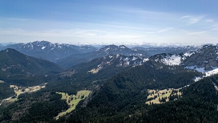 Obraz premium aerial view of the foothills of the Alps in Bavaria. Edge of mountains, sky and clouds. The mountains are covered with snow and forests.