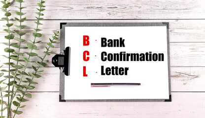 Board with the acronym BCL and its meaning bank confirmation letter on a wooden table with green...