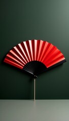 Elegant Red and Black Hand Fan Against a Deep Green Background Minimalist Still Life Photography