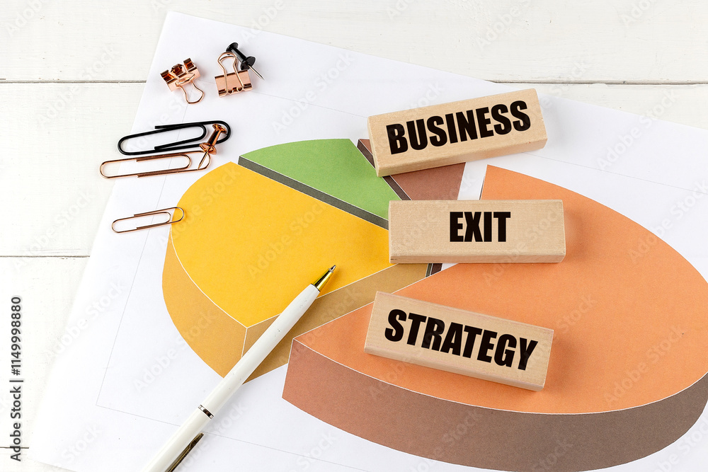Aufkleber wooden blocks with the text business exit strategy on a colorful pie chart surrounded by office supp
