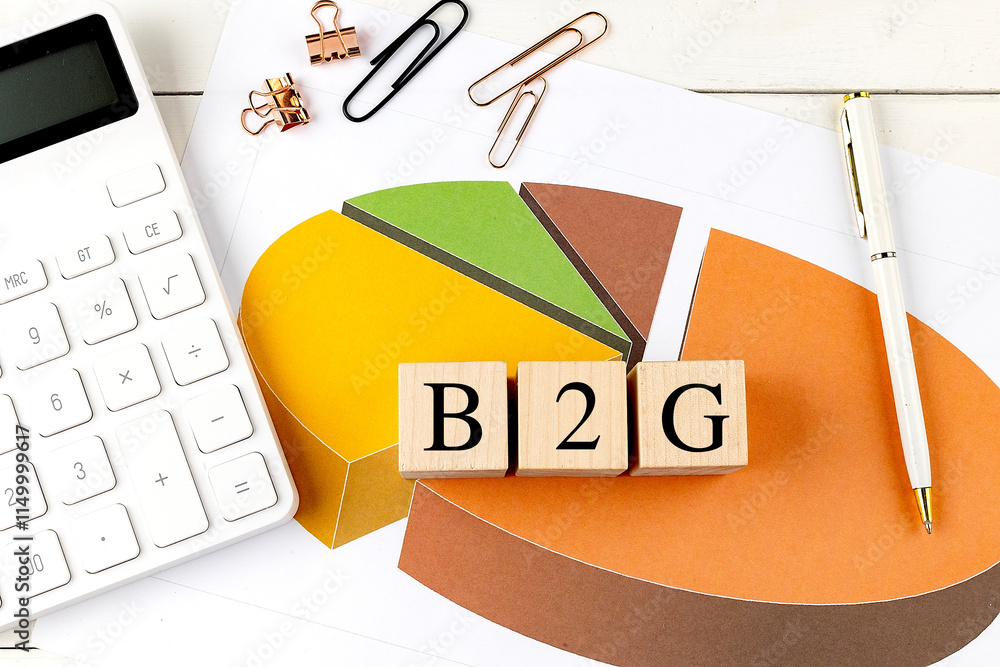 Poster wooden blocks with the text b2g on a colorful pie chart with a calculator and paper clips on a desk