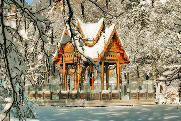 Westpark in Munich in winter full of snow.
The trees and benches are covered in snow.