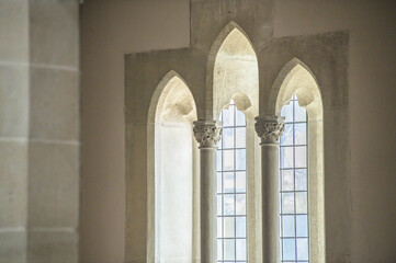 Gotisches Kirchenfenster mit Bleiverglasung hinter runden  Steinsäulen mit floralem Kapitell und...