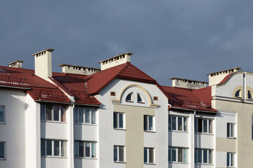 Part of modern architecture of multi-apartment residential building. Design. Idea. Facade. Window, balcony, roof, metal tile. Light and shadow