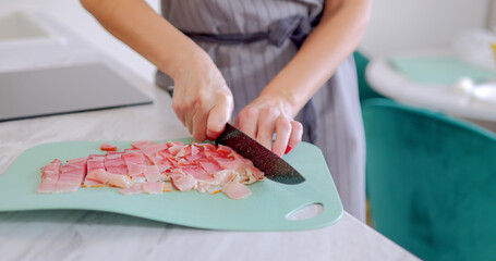 Woman Slicing Bacon on Green Cutting Board in Modern Kitchen