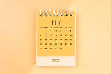 July 2025 mini desk calendar on the yellow, planning for business meeting.