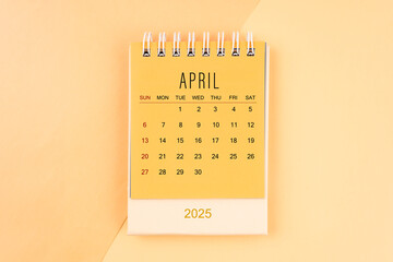 April 2025 mini desk calendar on the yellow, planning for business meeting.