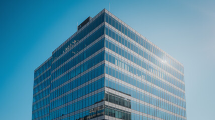 Obraz premium Modern Glass Office Building Against Blue Sky