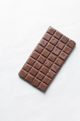 Overhead view of a dark chocolate bar, top view of a shiny chocolate bar on a white granite countertop