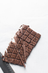 Overhead view of chopped dark chocolate on a white granite countertop, top view of dark chocolate chunks for baking