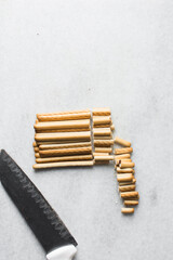 Overhead view of Chopped vanilla stick cookies on a marble countertop, stick cookies for dipping and baking