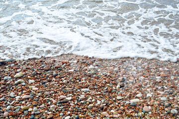 Beach holidays in the most beautiful places on the Montenegrin coast: a beach with pebbles of red, pink, white, grey, brown and other colours and the foamy waters of the Adriatic Sea in Sveti Stefan.