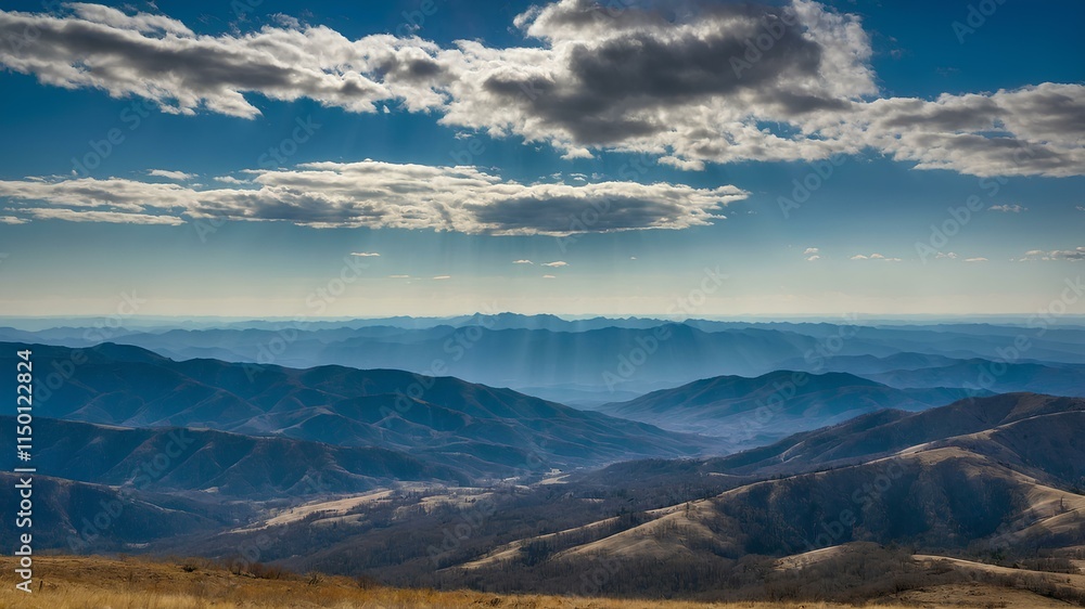 Poster sunbeams dramatically pierce through a dynamic cloudscape over a distant mountain range and golden p