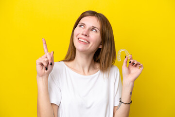 Young English woman holding invisible braces pointing up a great idea