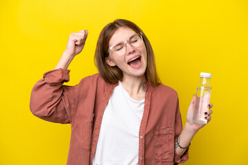 Young English woman with a bottle of water isolated on yellow background celebrating a victory