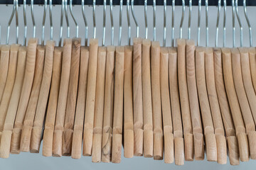 Wooden clothes hangers in row on rack in store closeup