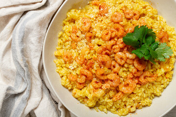risotto with shrimp, in a bowl, on a textured surface, with a side dish of fresh coriander, homemade, no people,