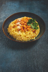 risotto with shrimp, in a bowl, on a textured surface, with a side dish of fresh coriander, homemade, no people,