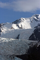 Sunlit snow topped mountain with a glacier in the foreground, College Fjord, Alaska USA
