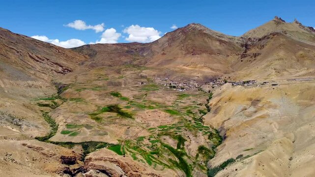 Aerial view of chicham village and spiti valley in the distance isolated by high himalayas under bright sky in summer at spiti valley himachal pradesh, India.