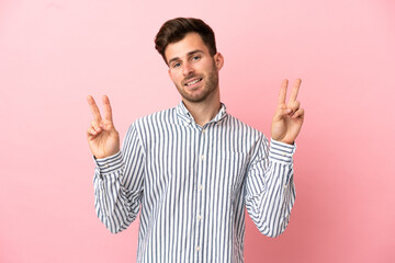 Fototapeta premium Young caucasian handsome man isolated on pink background showing victory sign with both hands