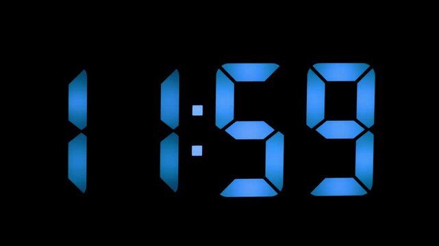 Digital clock displays time as eleven fifty-nine in blue light during late night hours in a dark room setting
