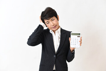 電卓を持ち困るスーツ姿の中高年の女性