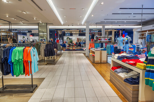 Interior Tommy Hilfiger men's clothing section inside Macy's store featuring neatly arranged racks, shelves, apparel displays. New York. USA.
