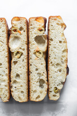 Overhead view of sliced homemade olive focaccia on a white countertop, top view of focaccia with green olive topping, fresh homemade focaccia bread