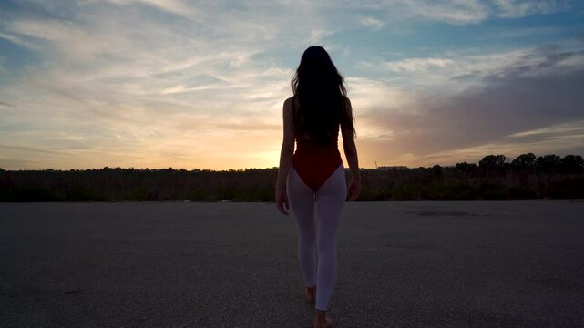 Chica bailarina de danza cl&aacute;sica anda por una pista de aterrizaje hacia la puesta de sol y realiza movimientos bonitos y elegantes de baile como conceptos de viajes, arte y energ&iacute;a.