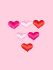 Triangle arrow made of glossy atlas hearts isolated on solid pink background. Love alphabet concept. One punctuation mark of the set of heart's font easy to stacking