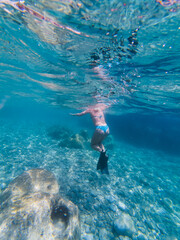 A woman in a swimsuit snorkels in the Mediterranean Sea on de la Gavinette beach in the south of France. Vertical photo.