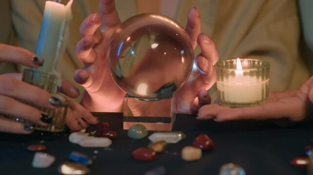 Handheld shot of young Asian girl predicting on crystal ball while fortune telling with her friends at night