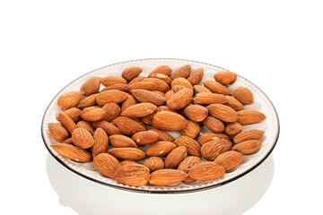 Fragrant roasted almonds in a ceramic saucer, close-up, isolated on a white background.