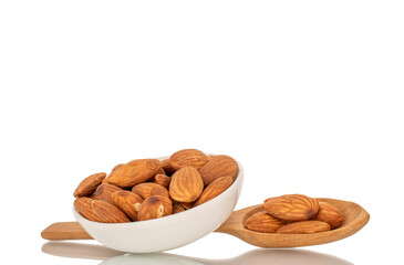 Fragrant roasted almonds in a ceramic saucer, close-up, isolated on a white background.