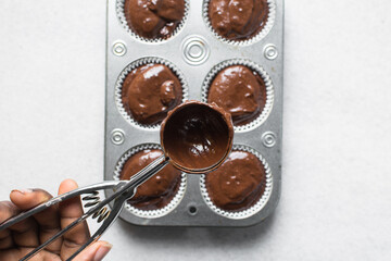 Overhead view of chocolate muffin batter in a cookie scoop, process of making dark chocolate muffin