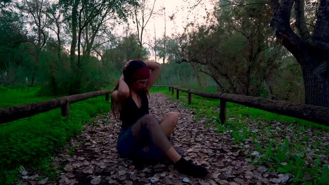 Chica joven llorando y sufriendo en un sendero del bosque al atardecer.