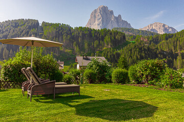 Garden with sunbeds and umbrella. Sassolungo massif in the background, South Tyrol, Italy