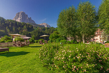 Garden with sunbeds and umbrella. Sassolungo massif in the background, South Tyrol, Italy