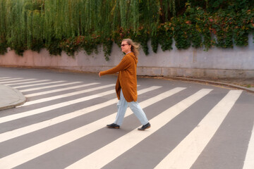 Middle aged woman crossing the road on a pedestrian crossing. Full-length portrait of a mature...