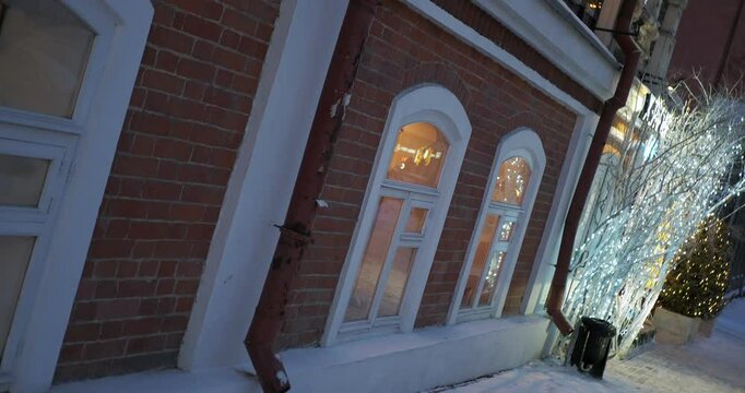 Christmas decorations. The branches of the tree placed next to the windows are beautifully decorated with bright garlands. Hend held.Camera rotation. Siberia.