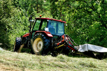 Obraz premium Tractor cutting grass in a field prior to drying and baling 
